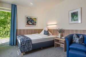 um quarto de hotel com uma cama e uma cadeira azul em Hotel Am Moosfeld em Munique