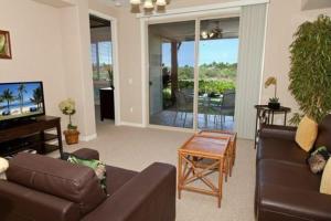 uma sala de estar com um sofá, uma mesa e uma televisão em Palm Villas G1 32 em Waikoloa