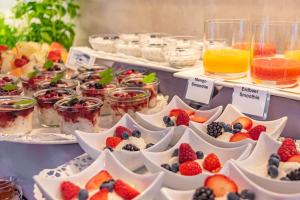 un buffet lleno de postres y fruta en tazones blancos en Parkhotel Sonnenberg, en Eltville am Rhein