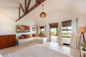 a bedroom with a bed and a couch and a window at Rare Beachfront Villa - 2BR - 6 Pax Private Pool on Tuason Surf Spot in General Luna