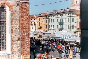 una multitud de personas caminando por un mercado con sombrillas en Ca' Garibaldi Rooms en Bassano del Grappa