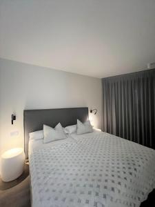 1 dormitorio con 1 cama grande y edredón blanco en Apartaments Turístics Conseller, en Andorra la Vella