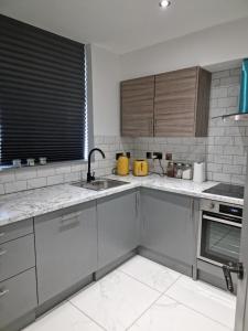a kitchen with gray cabinets and a sink at Remarkable 3-Bed Apartment in London in London