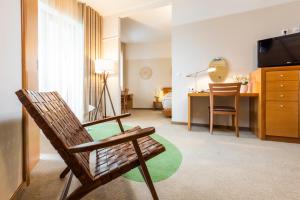 a living room with a chair and a television at Hotel Livada Prestige - Terme 3000 - Sava Hotels & Resorts in Moravske-Toplice