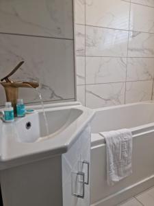 uma casa de banho branca com um lavatório e uma banheira em Remarkable 3-Bed Apartment in London em Londres