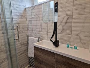 a bathroom with a sink and a shower with a mirror at Remarkable 3-Bed Apartment in London in London