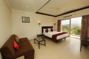 a bedroom with a bed and a couch and a window at Bella Vista Mahabaleshwar in Mahabaleshwar