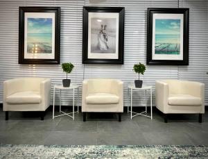 a wall with three chairs and two tables with plants at Athenian Riviera Hotel& Suites in Athens