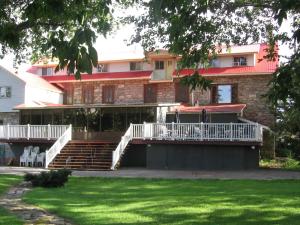 - un bâtiment avec des escaliers, une terrasse couverte et une pelouse dans l'établissement Hostellerie du Suroît, à Beauharnois