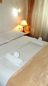 two beds with white sheets and a lamp on a table at Hotel Slavonija in Vinkovci