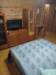 a bedroom with a bed and a flat screen tv at Гостевой дом Azia in Borovoye
