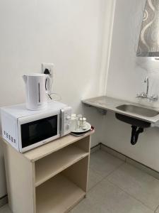 a microwave sitting on a table next to a sink at Ikhaya Guesthouse in Empangeni