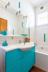 W łazience znajduje się niebieska umywalka i wanna. w obiekcie Villa à 2 pas de la plage w Arcachon