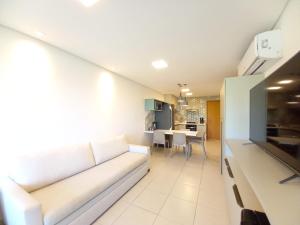 a living room with a white couch and a kitchen at Praia dos Carneiros Flat 206 C in Tamandaré