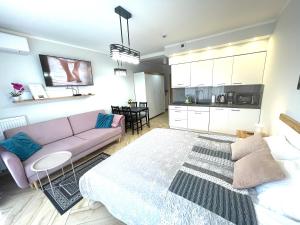 a living room with a purple couch and a kitchen at Apartament Superior Lawendowy z Tarasem in Kołobrzeg