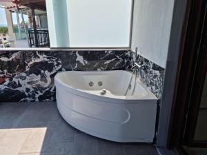 biała wanna w pokoju ze ścianą w obiekcie Lux Suite Sea Front Avra w mieście Pefkochori