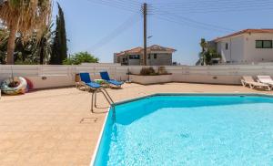 a swimming pool with two chairs and a house at Mediterranean dream in Voroklini