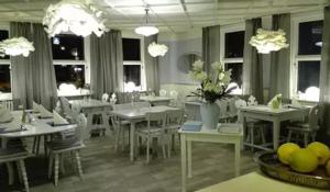 Klosterhotel Walkenried في Walkenried: غرفة طعام بمناضد بيضاء وكراسي وأضواء