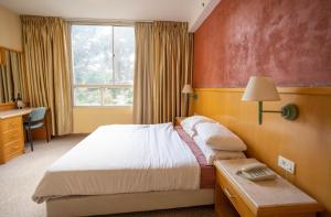 a bedroom with a bed and a desk and a window at Marom Hotel in Haifa