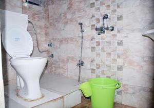 La salle de bains est pourvue de toilettes et d'un seau vert. dans l'établissement The Candy Heights, à Rānchī