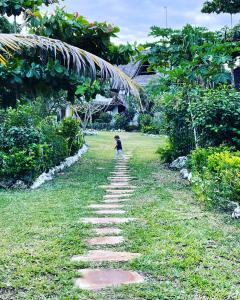 a child walking down a path in the grass at Botanica Eco Lodge in Michamvi