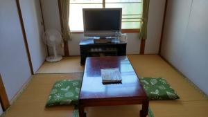 una pequeña sala de estar con mesa y TV. en Guest House Yamada, en Date