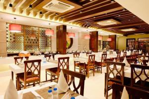 The Imperial Kushinagar في Kushinagar: غرفة طعام مع طاولات وكراسي في مطعم