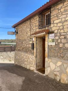 ein Steingebäude mit einer Tür und einem Schild darauf in der Unterkunft Casa Rural La Mansion in La Toba