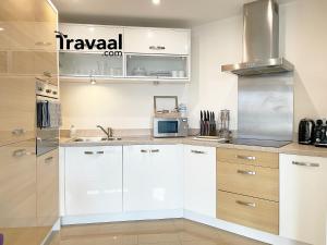 a kitchen with white cabinets and a microwave at Travaal.©om - 2 Bed Serviced Apartment Farnborough in Farnborough