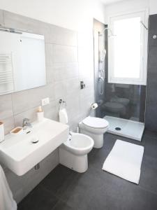 a white bathroom with a sink and a toilet at Dimora Mothia in Marsala