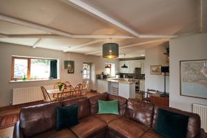 a living room with a brown leather couch and a kitchen at Brofallen- Spacious pet friendly bungalow with amazing coastal views in Laugharne