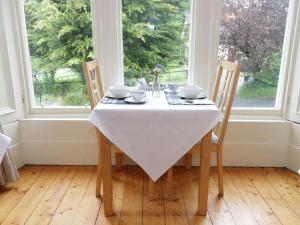 una mesa con 2 sillas y un mantel blanco en Allerton House, en Jedburgh