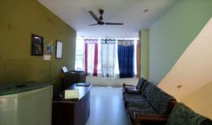 uma sala de estar com um sofá e uma ventoinha de tecto em New Agra Guest House By WB Inn em Agra