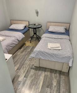 two twin beds in a room with a table at MR Guest House in Tbilisi City