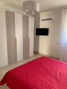 1 dormitorio con cama roja y TV en CASA VACANZE RE DEL MARE en Taranto