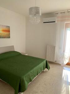 Habitación blanca con cama verde y lámpara de araña. en CASA VACANZE RE DEL MARE en Taranto