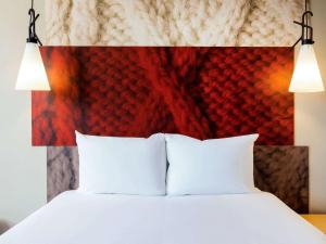 a bed with white pillows and a red headboard at ibis Gent Centrum Opera in Ghent