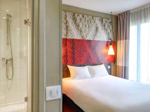 a bedroom with a white bed and a shower at ibis Gent Centrum Opera in Ghent