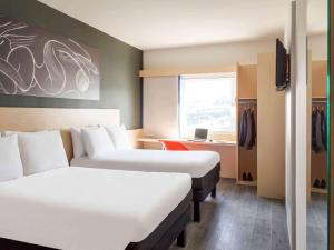 a hotel room with two beds and a desk at Ibis Queretaro in Querétaro