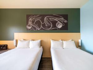 2 Betten in einem Zimmer mit Wandgemälde in der Unterkunft Ibis Queretaro in Querétaro