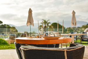 a wooden table with chairs and glasses on a patio at Golden Tulip Porto-Vecchio in Porto-Vecchio