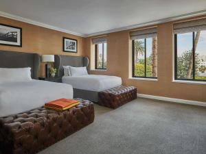 a hotel room with two beds and a couch and windows at Fairmont Miramar Hotel & Bungalows in Los Angeles