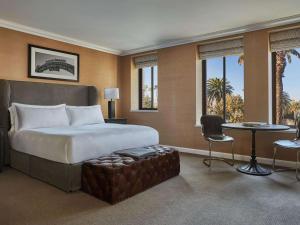 a bedroom with a large bed and a table and chairs at Fairmont Miramar Hotel & Bungalows in Los Angeles