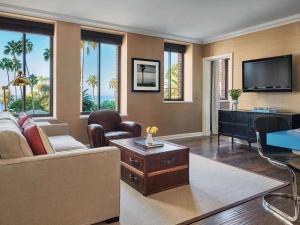 a living room with a couch and a tv at Fairmont Miramar Hotel & Bungalows in Los Angeles
