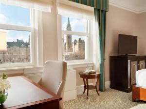 une chambre d'hôtel avec une table et deux fenêtres dans l'établissement Fairmont Chateau Laurier, à Ottawa