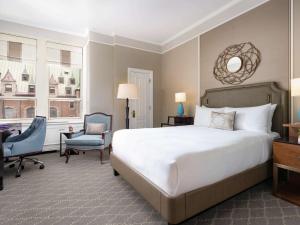 a bedroom with a bed and a desk and a chair at Fairmont Le Chateau Frontenac in Quebec City