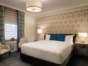 a bedroom with a large bed with blue pillows at Fairmont Empress Hotel in Victoria