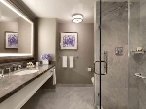 a bathroom with a shower, sink, and mirror at Fairmont Olympic Hotel in Seattle