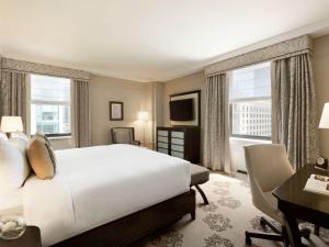 a bedroom with a large white bed and a desk and window at Fairmont Hotel Vancouver in Vancouver