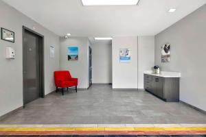 a hallway with a red chair in a room at Studio 6 Waco Downtown Baylor in Waco